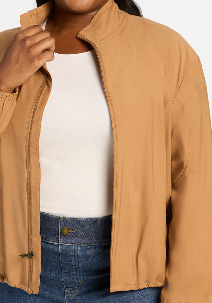A tan Cooper Windbreaker - Saddleback worn over a white top and blue jeans.