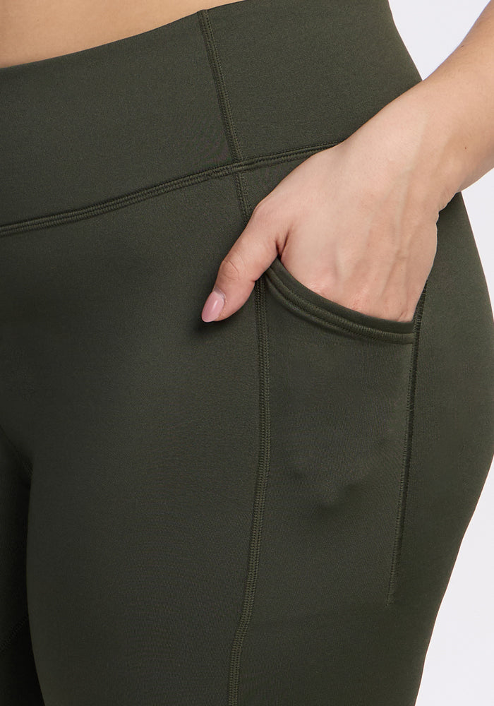 Close-up of a person wearing Woolx Merino Flex® Dani Bike Shorts in Everleaf, with their right hand in the side pocket. The shorts feature moisture-wicking fabric, visible stitching, and a high waistband.