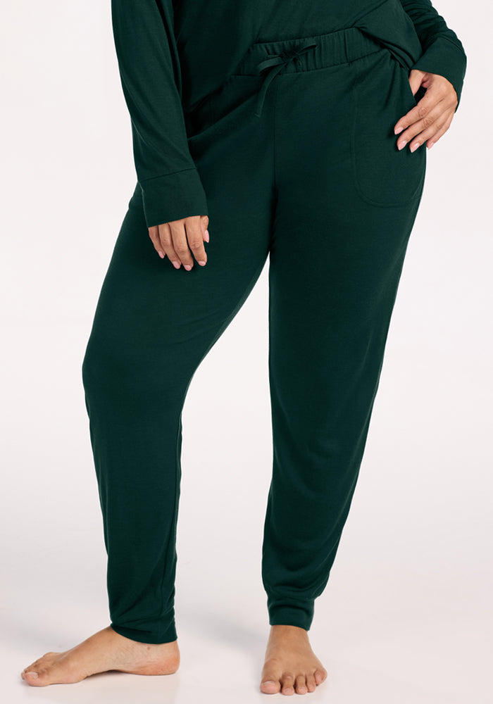Woolx Mary Kate Lounge Pants in Deep Pine, featuring dark green moisture-wicking fabric, a drawstring waist, and pockets. 