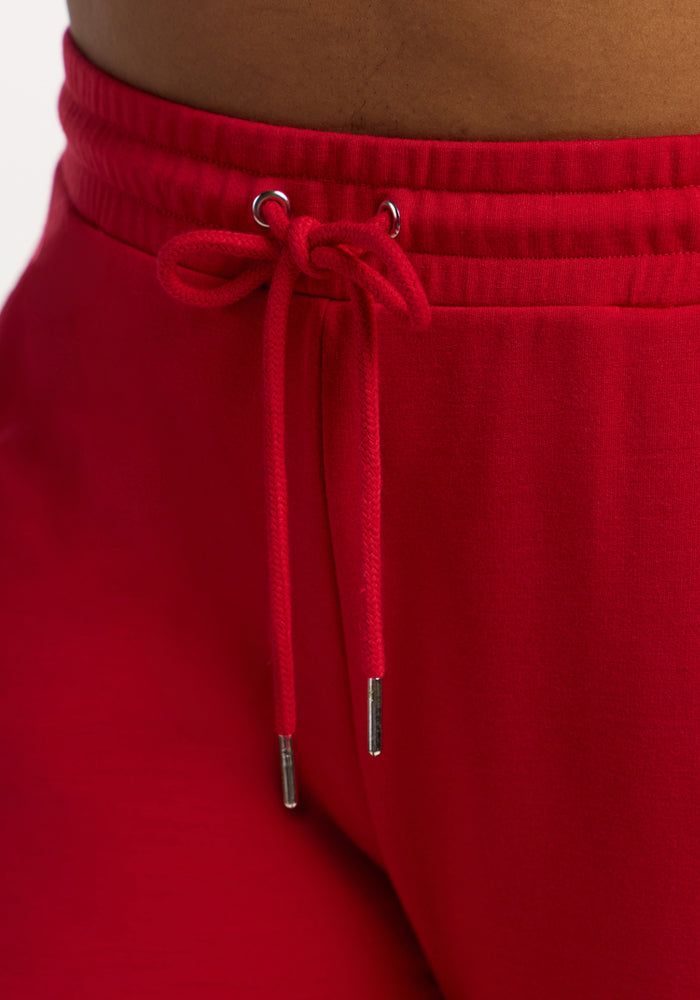 Close-up of a person wearing Woolx Eloise Wide Leg Pants in Maraschino Cherry with a tied drawstring waistband.