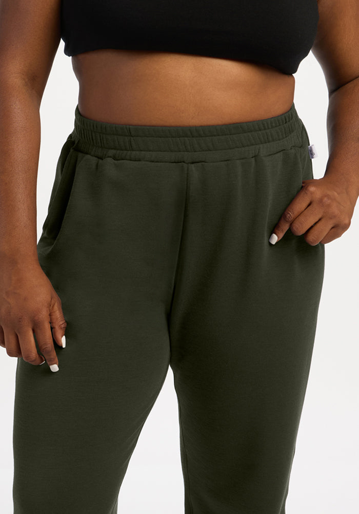 Person in a black top and Woolx Parker Sweatpants - Duffel Bag, hands in pockets, shown mid-torso to thighs.