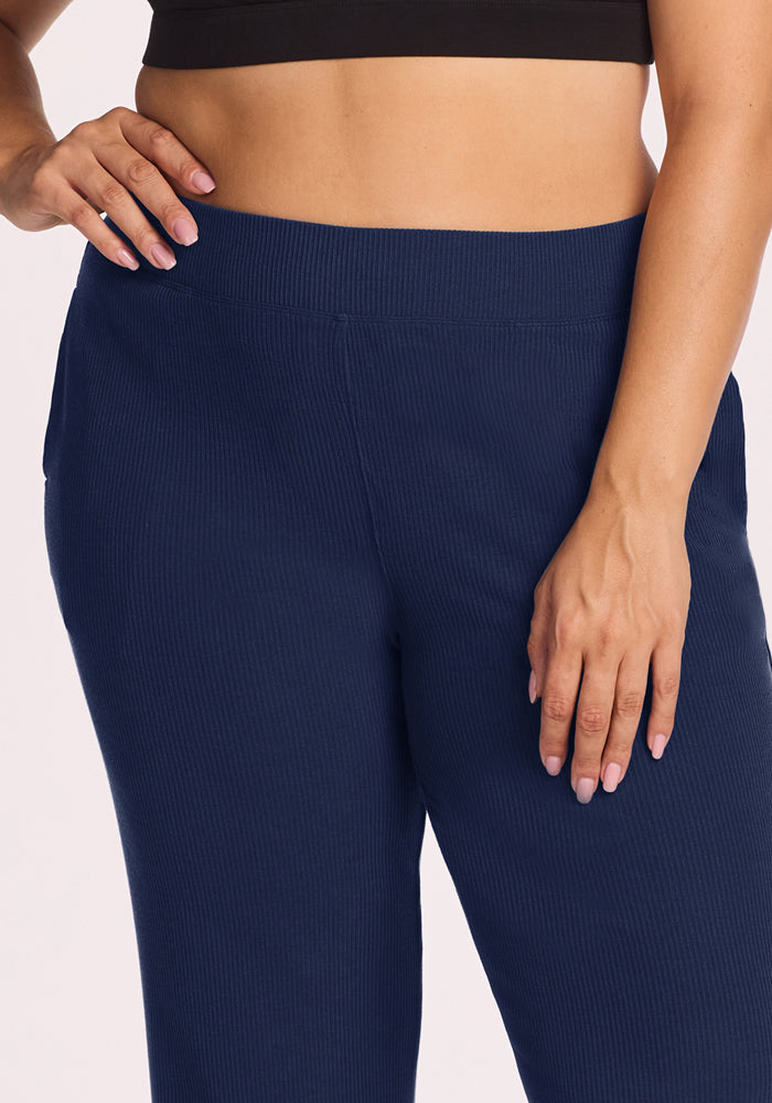 Person wears a black crop top and Woolx Luca Ribbed Pants - Ocean Cavern, one hand resting casually on their hip.