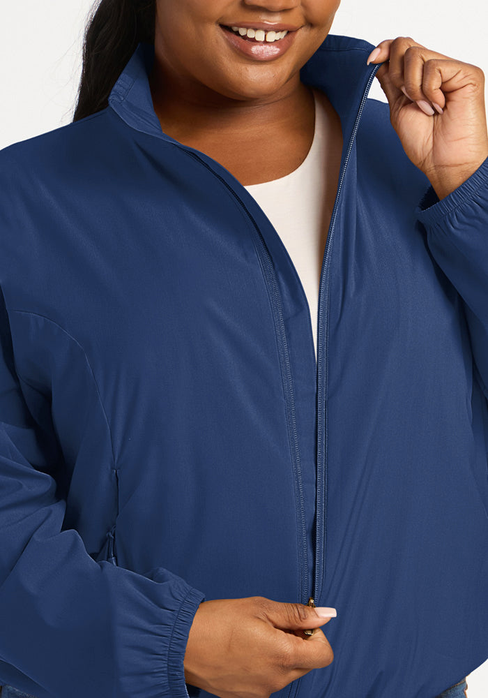 A person wearing a dark blue Cooper Windbreaker - Vintage Indigo zippered layering jacket.