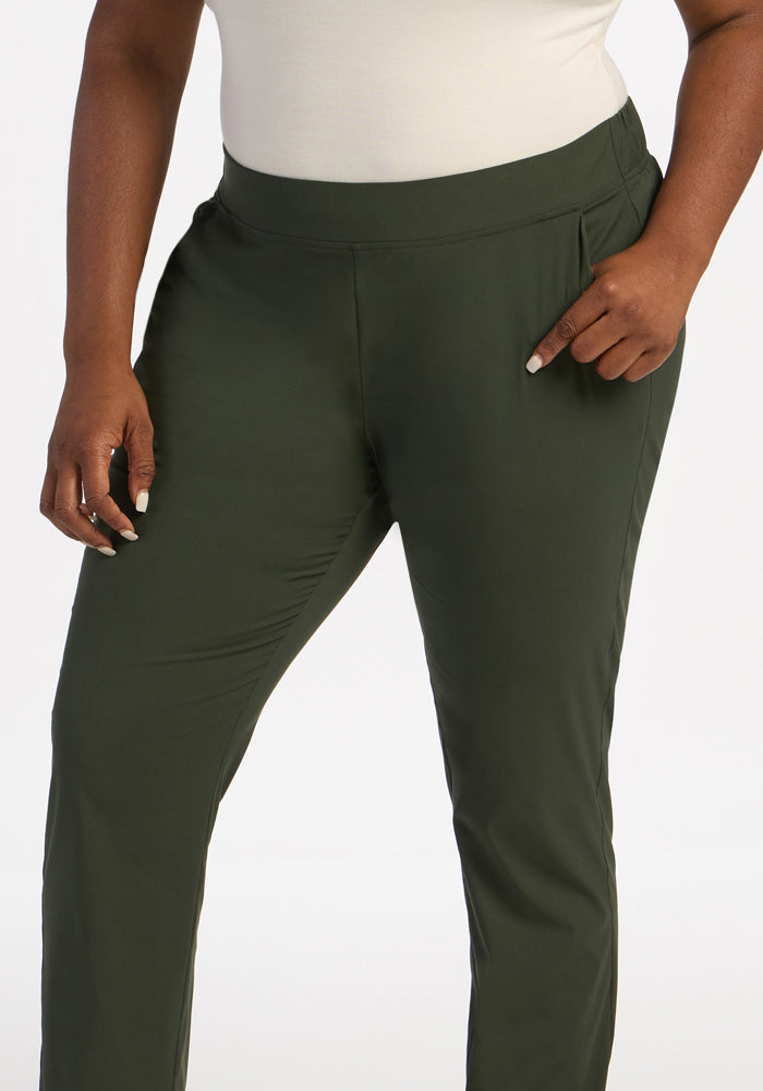 Model wears Woolx Nicole Ankle Pants in Duffel Bag with a white top, hand in pocket, against a white background.