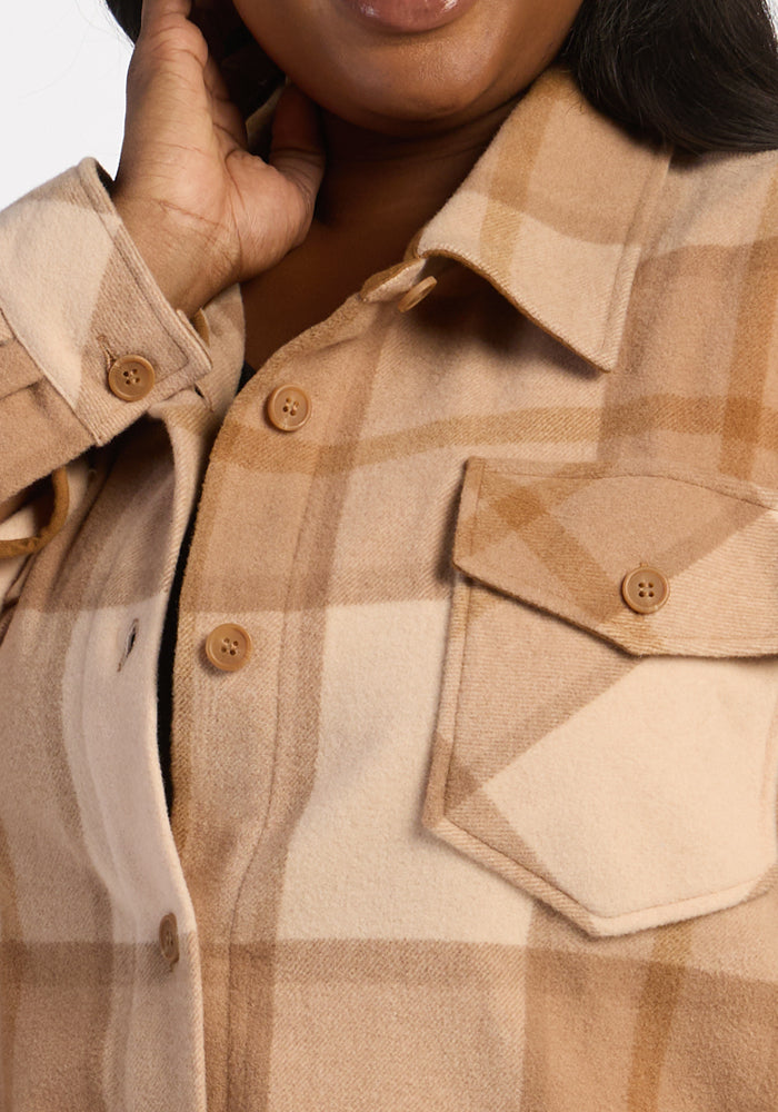 A person wears the Woolx Sawyer Shacket in Saddleback Plaid, featuring a chest pocket, touching their neck.