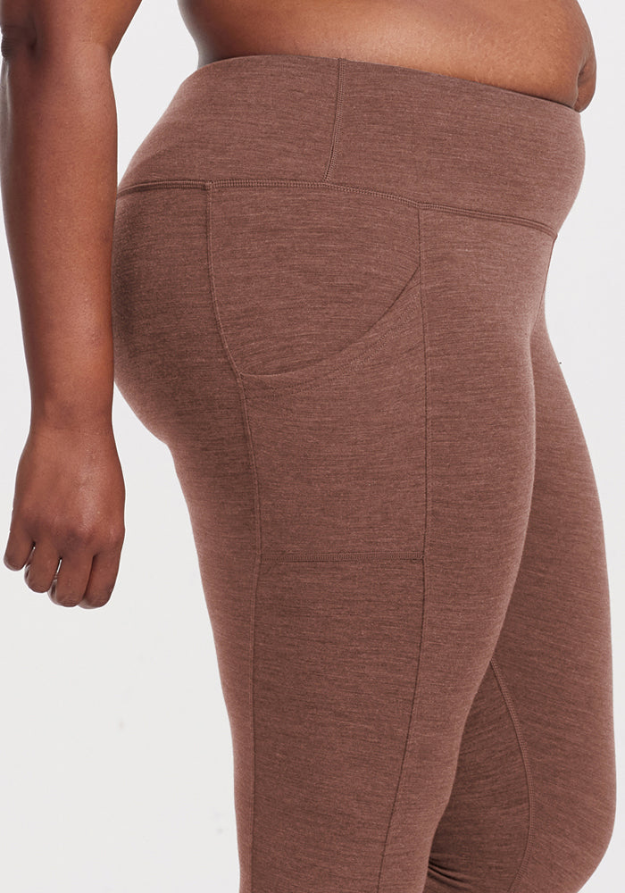 A person wears Woolx Piper Pocket Tall leggings in Sable Heather, shown waist to mid-thigh on a plain background.