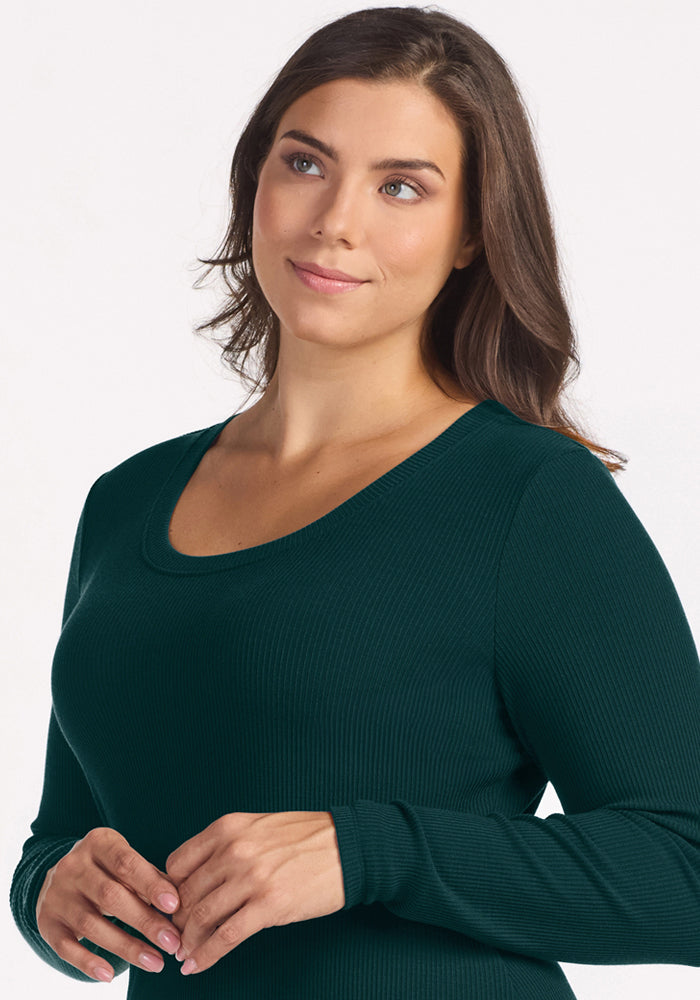 Woman with long brown hair wears Woolx Caroline Ribbed Twirl Dress in Deep Pine, gazing upward and smiling softly.
