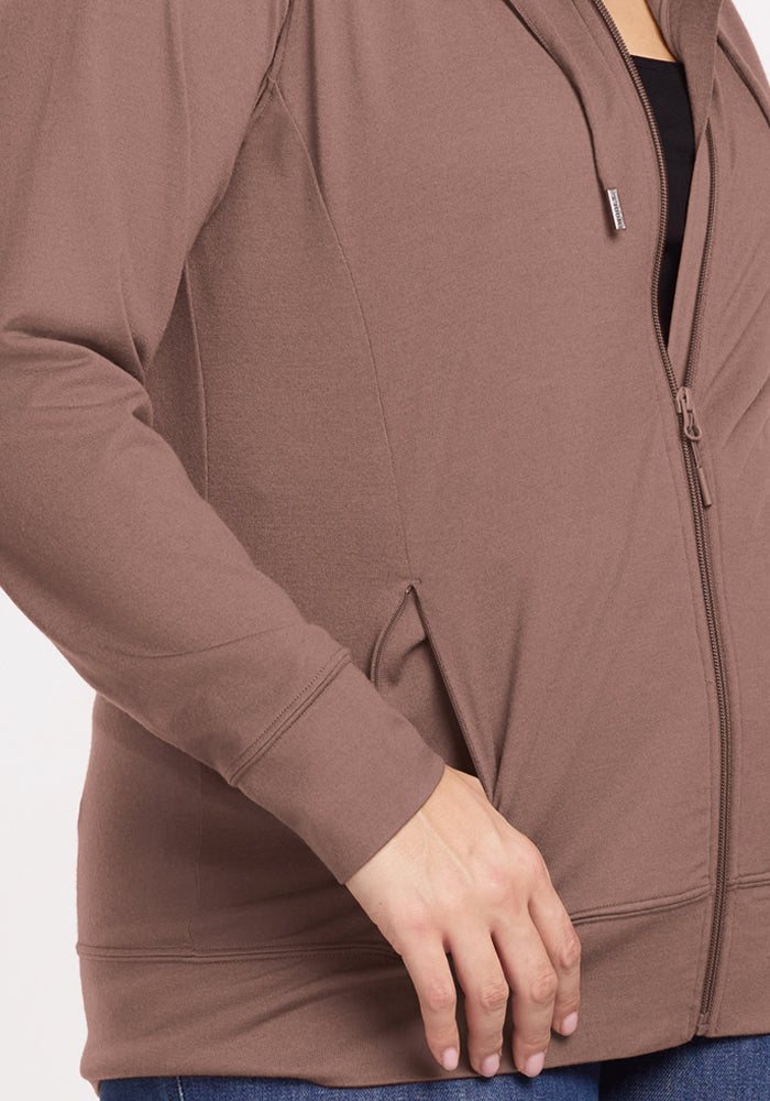 Person wearing Woolx Ryann Hoodie in Toasted Almond, black shirt underneath, blue jeans, hand near pocket.