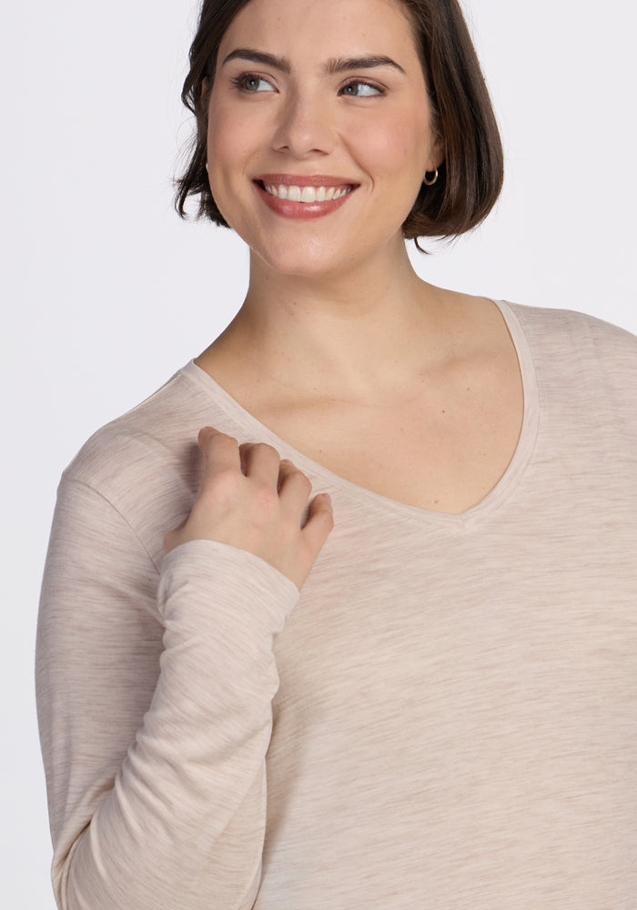 A woman with short brown hair, wearing the Woolx Millie Long Sleeve in Cream Heather, smiles and looks slightly to the side against a plain white background.