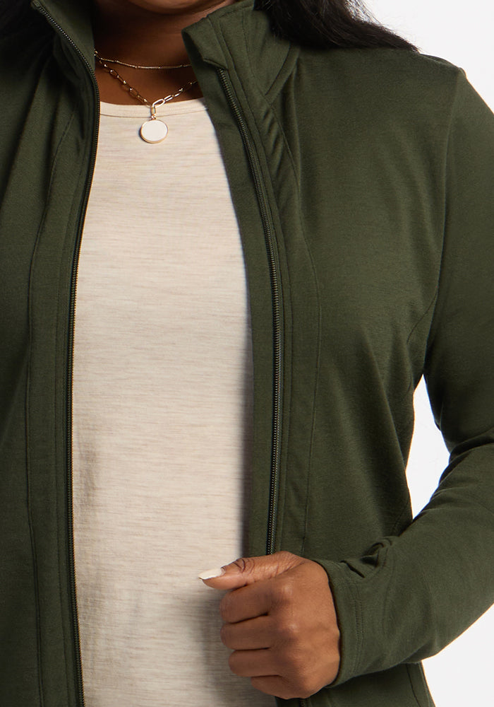 Woman in a Woolx Finley Zip Up Sweatshirt - Duffel Bag over a cream shirt, holding the zipper with her right hand.