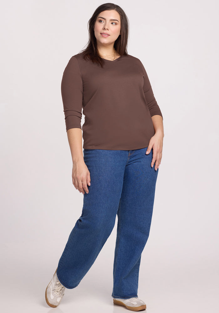 Woman wearing the Woolx Elena 3/4 Sleeve V Neck in Peppercorn, blue jeans, and white sneakers against a light background.