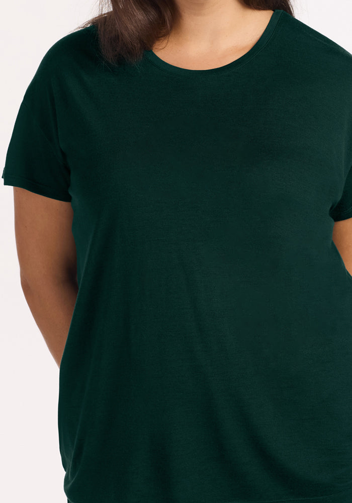A person wearing a dark green Billie Lounge Tee - Deep Pine, a short-sleeved moisture-wicking crew neck t-shirt.