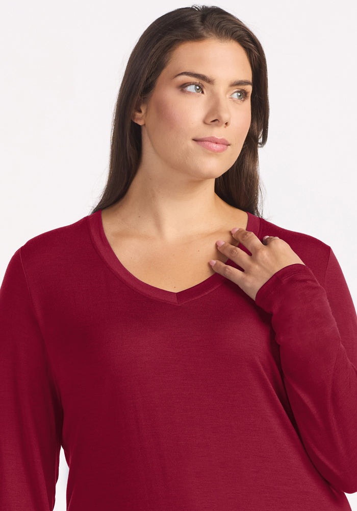 A person wearing a long-sleeved, beet red Merino wool Lily V Neck Lounge Top.