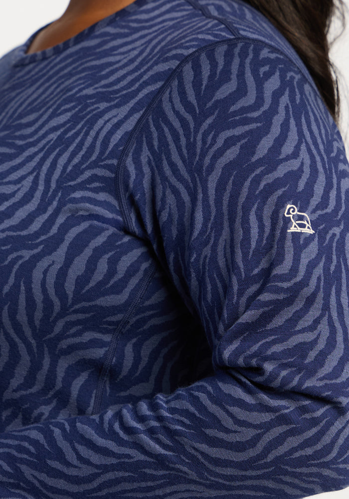 Close-up of Woolx Maddie Baselayer Top - Midnight Safari, featuring blue zebra stripes and a white logo on the sleeve.