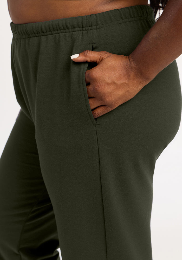 A person with dark skin models Woolx Juliette Joggers - Duffel Bag, one hand in pocket, against a white background.