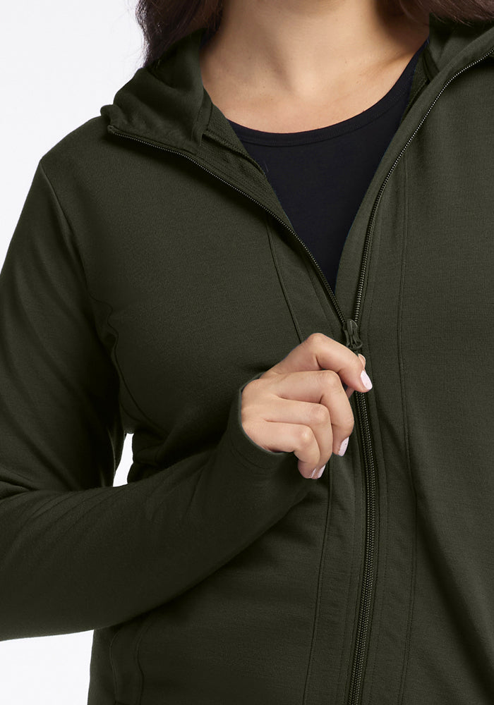 Person zipping up a Woolx Zoey Zip Up Hoodie - Duffel Bag over a moisture-wicking black top, only upper body visible.