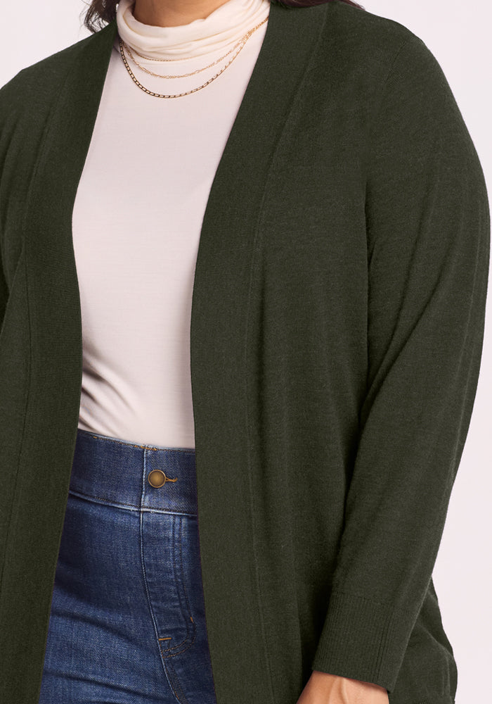 Woman wearing the Woolx Macie Sweater in Duffel Bag over a white turtleneck, blue jeans, and a gold necklace.
