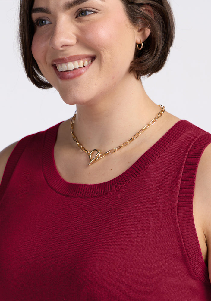 Woman smiling, wearing the Woolx Chessy Tank Top in Beet Red and a chunky gold chain necklace with heart clasp.