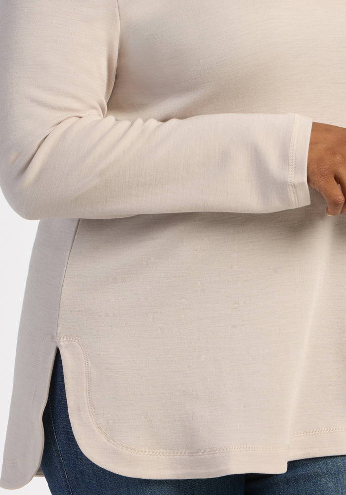 A person in the Woolx Blair Tunic - Ecru with side slits and blue jeans, shown from shoulder to hip.