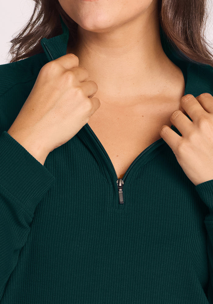 Someone in the Woolx Quinn Ribbed 1/4 Zip - Deep Pine, unzipping the Merino wool collar partway.