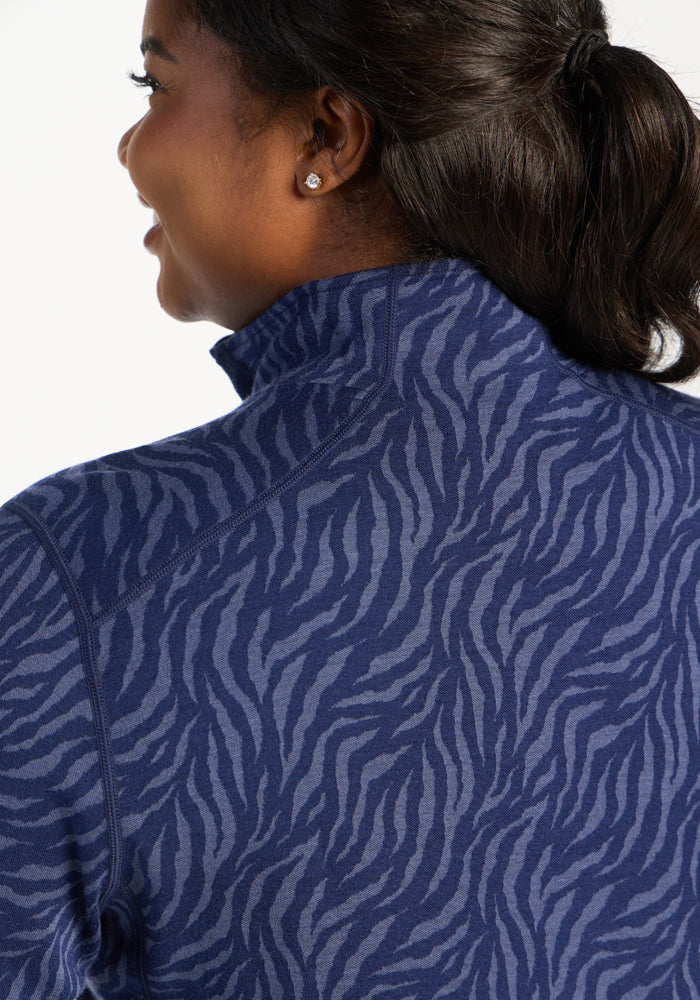 Woman with dark hair in a ponytail wears Woolx Emi 1/4 Zip - Midnight Safari jacket, facing away.