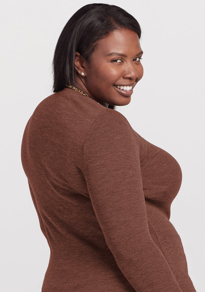 Woman in a Woolx Reese Ribbed Henley in Sable Heather smiling over her shoulder against a plain light background.