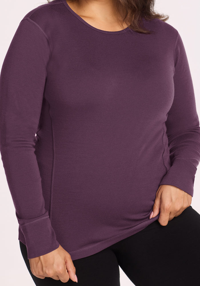 Person wearing a Woolx Hannah Long Sleeve Top - Purple Iris and black pants, shown shoulders to hips, hand by side.