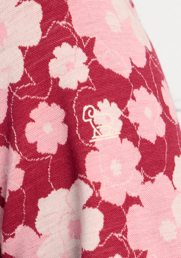 Close-up of Woolx Maddie Baselayer Top - Floral Crush, with a red-pink floral print and small white dog logo.