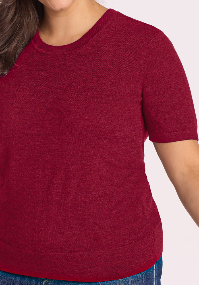 Model in Woolx Anna Crew Sweater - Beet Red and blue jeans, shown shoulder to waist against a light background.