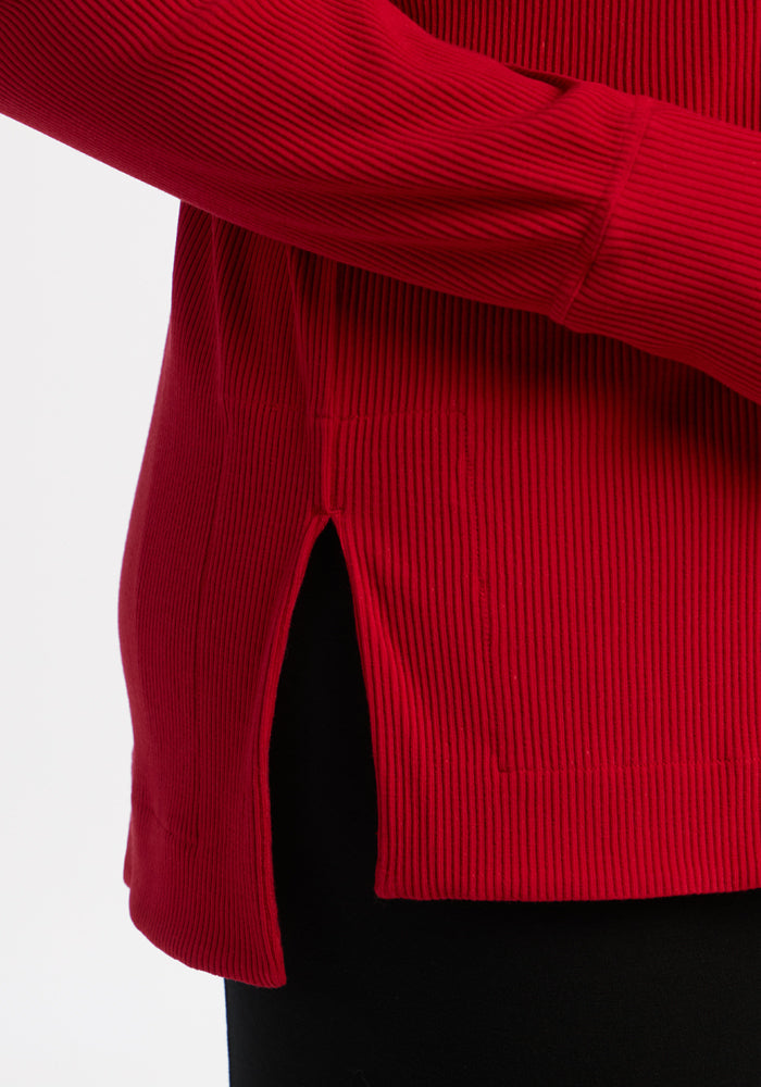 Close-up of the Woolx Ainsley Sweater in Maraschino Cherry, styled with black pants against a white background.