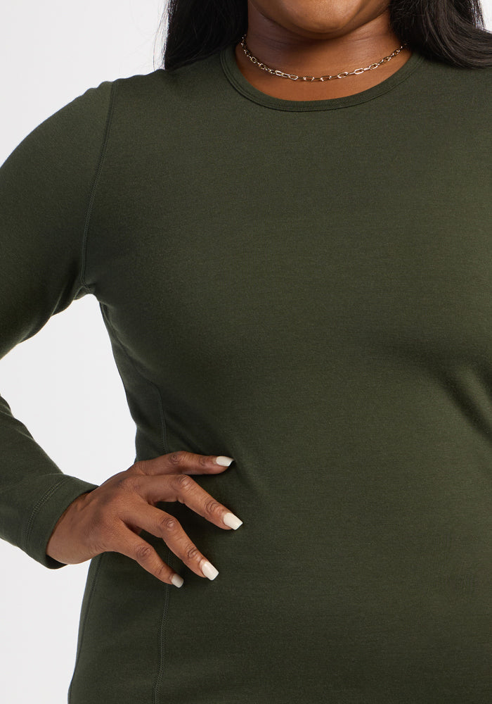 Model wears Woolx Elsa Long Sleeve - Duffel Bag and a gold necklace, hand on hip, against a white background.