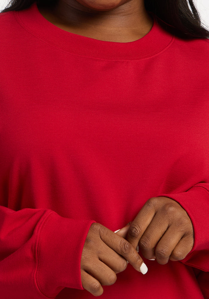 Close-up of a person wearing a bright red moisture-wicking Molly Crewneck - Maraschino Cherry merino wool sweatshirt.