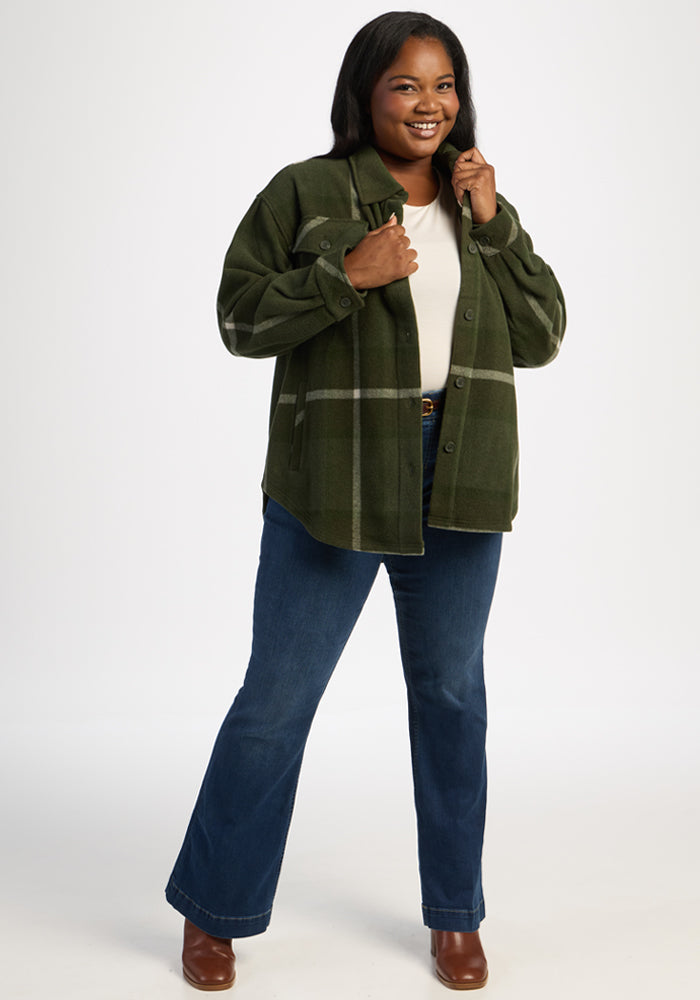 Woman in Sawyer Shacket - Driftwood Fern Plaid by Woolx, white top, blue jeans, brown boots against white background.