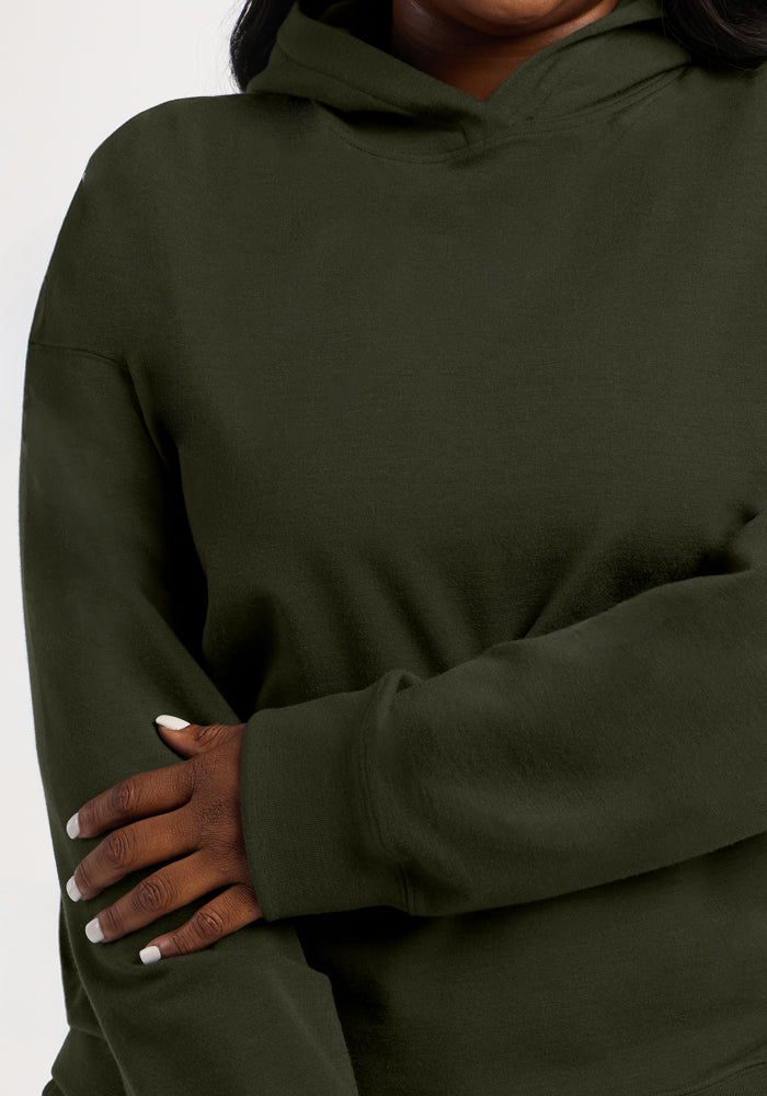 A person wearing a dark olive green Genevieve Hoodie - Duffel Bag made of moisture-wicking merino wool.