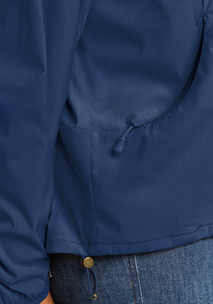 Close-up of a blue Woolx Cooper Windbreaker - Vintage Indigo featuring a zippered pocket and a drawstring hem.