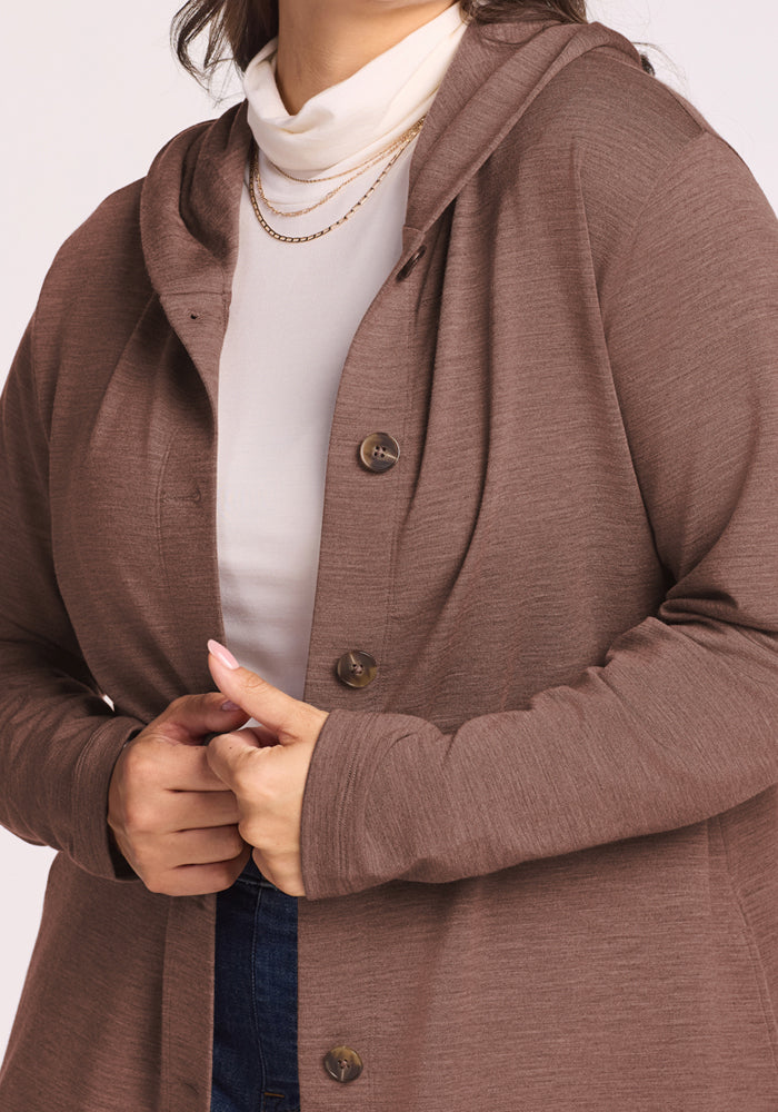 Woman in the Woolx Edna Hooded Cardigan in Sable Heather over a white turtleneck, hands clasping the lapel.