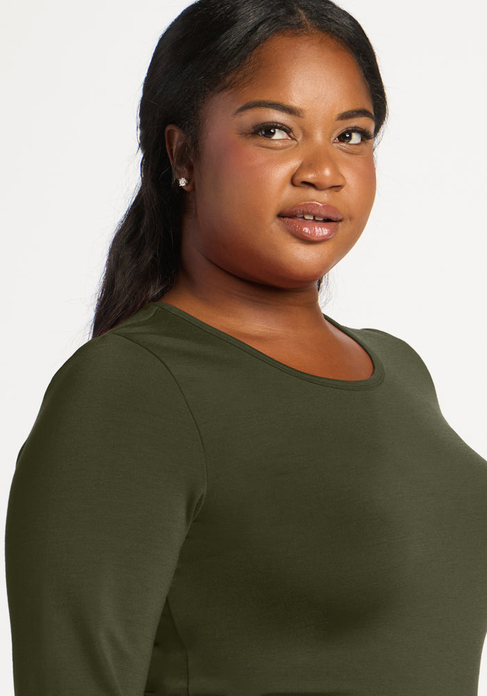 Woman with long dark hair in the Woolx Margot Bodysuit - Everleaf, looking at camera against white background.