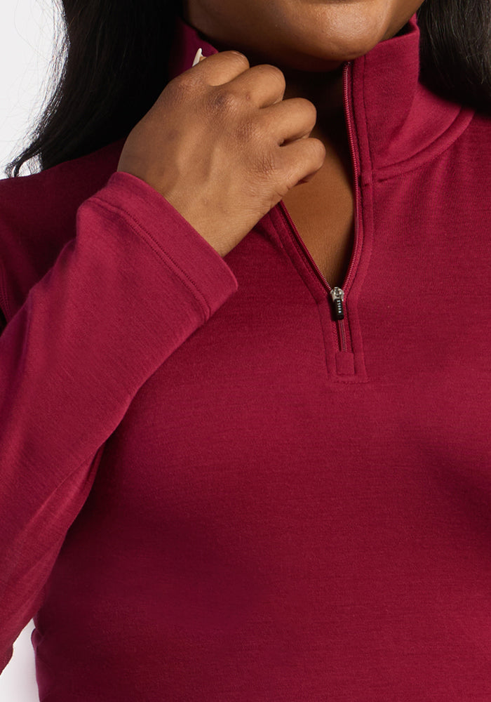 Person in a Woolx Brooke 1/4 Zip - Beet Red pulling up the zipper, focus on hand and upper torso.