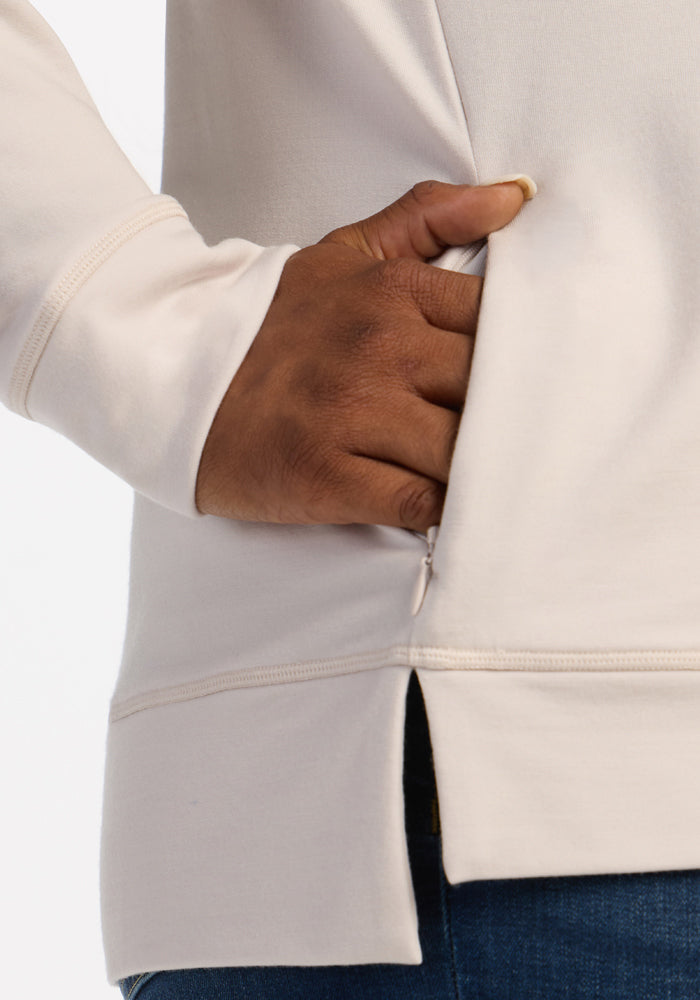 A hand slips into the side pocket of the Woolx Annie 3 Button Pullover - Ecru, styled with blue jeans.