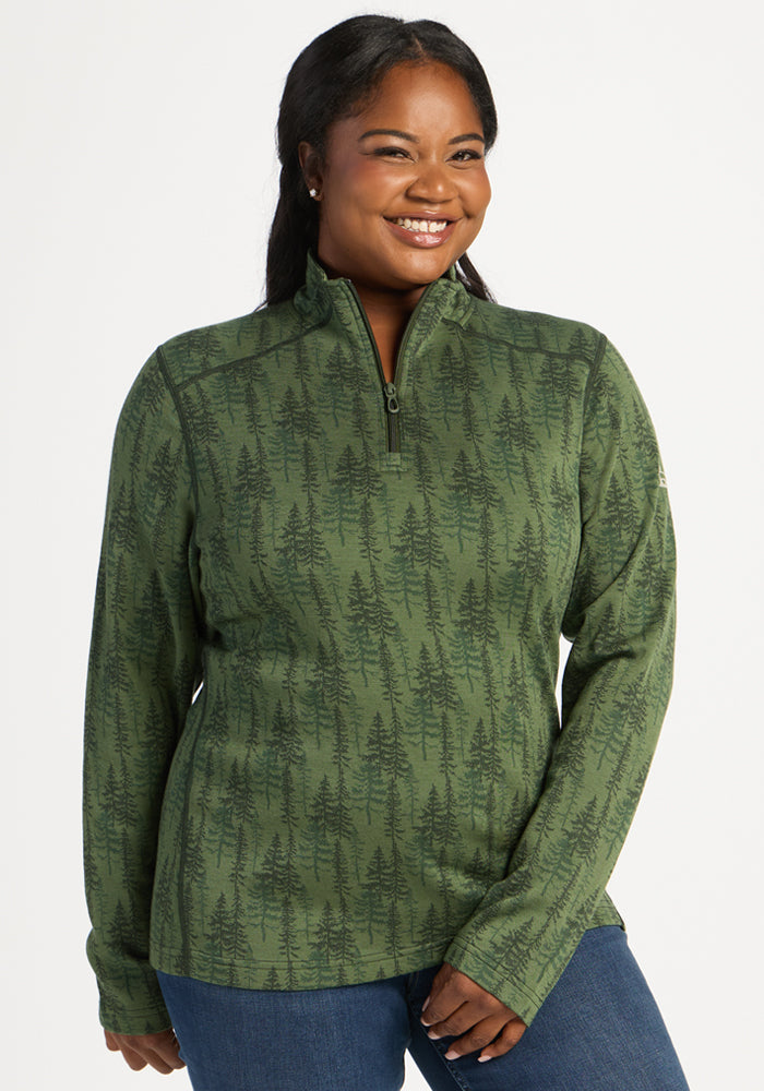 Smiling woman in Woolx Emi 1/4 Zip - Forest Friends, long-sleeve green base layer, against white background. 