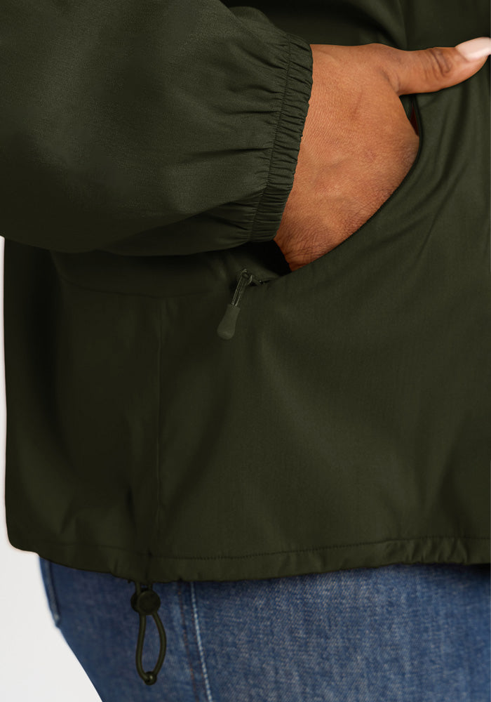 Close-up of a person wearing a dark green Cooper Windbreaker - Duffel Bag with a zippered pocket.