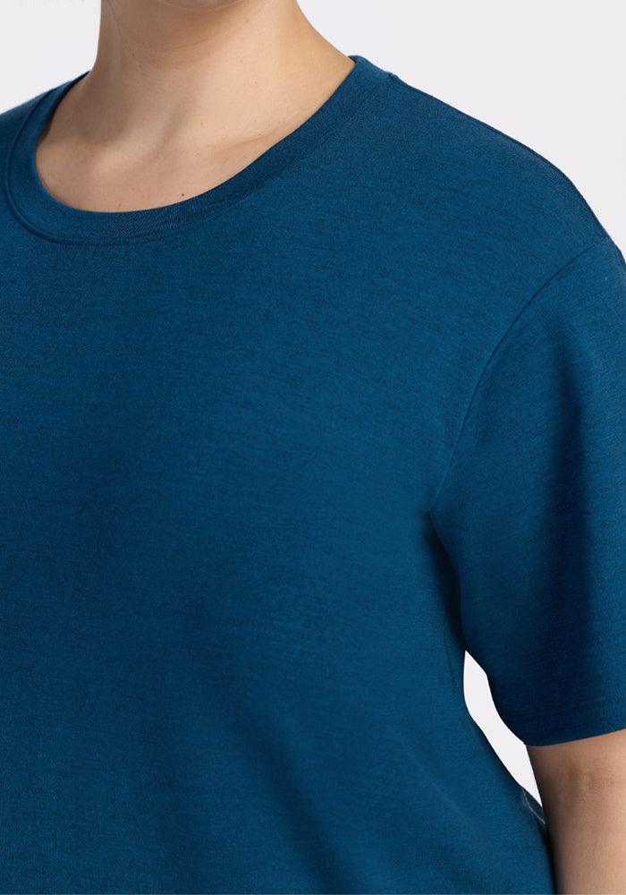 Close-up of a person wearing the Woolx Audrey Tee in Majolica Blue, showcasing the upper chest, neck, and shoulder against a plain light background.