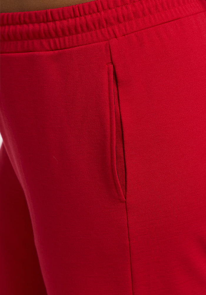 Close-up of a person wearing Woolx Eloise Wide Leg Pants in Maraschino Cherry, featuring an elastic waist and pocket.