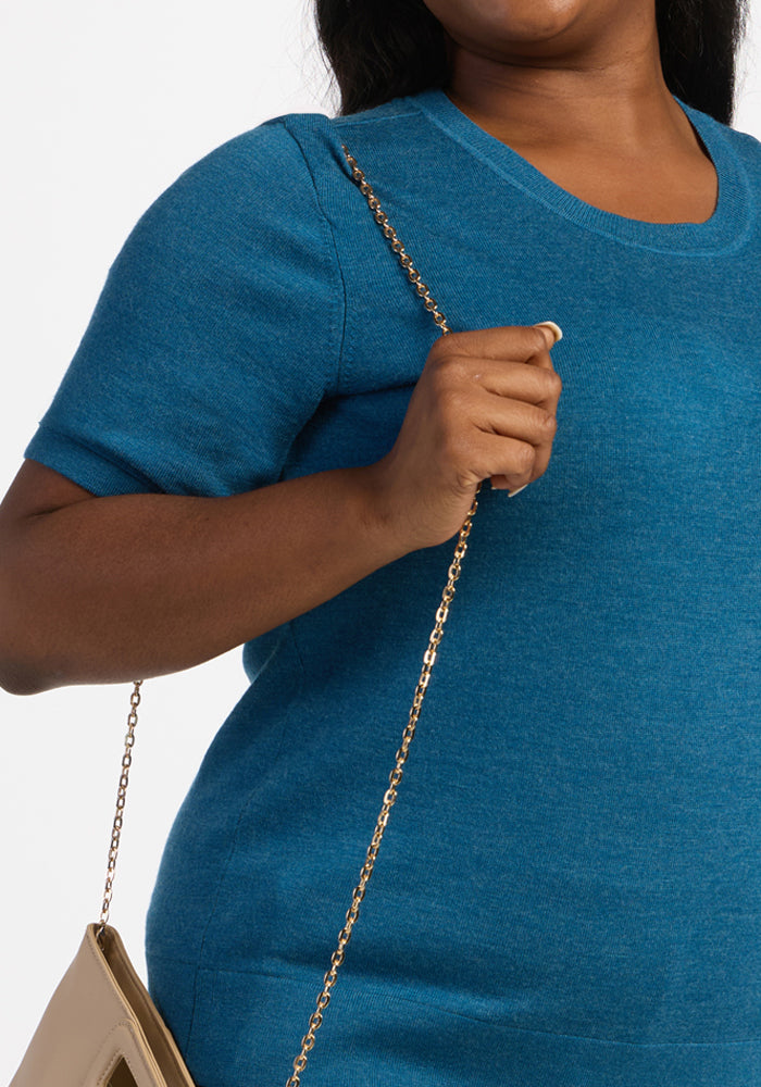 Woman in blue Woolx Anna Crew Sweater holding a beige purse with a gold chain strap over her shoulder.