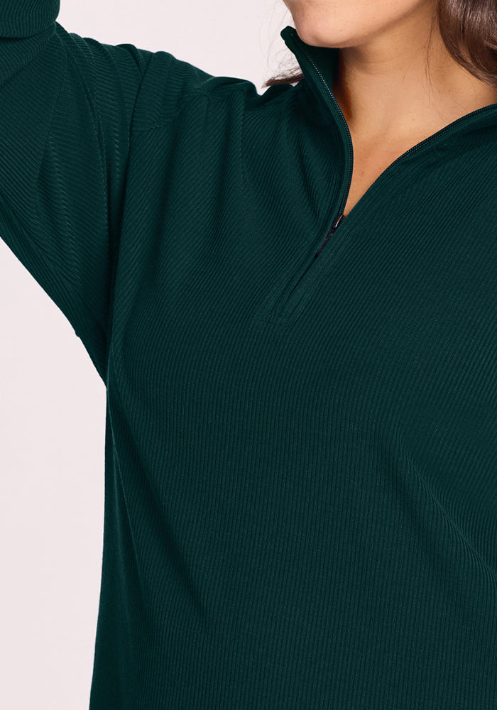 Woman in Woolx Quinn Ribbed 1/4 Zip - Deep Pine, arm raised, face partially visible.