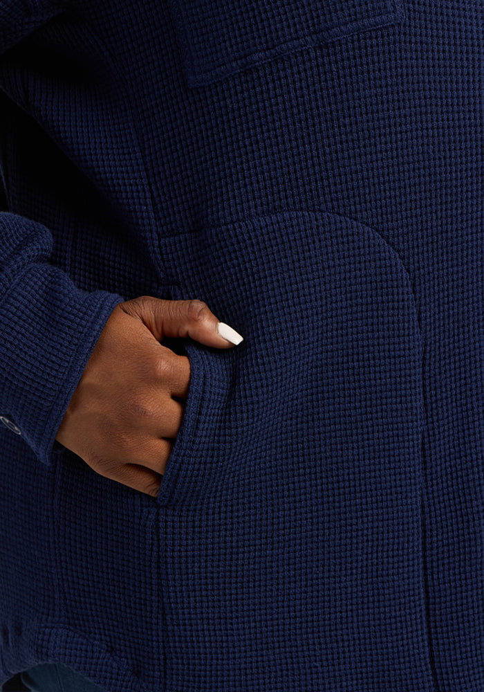 A hand with light nail polish rests in the pocket of the Woolx Oaklynn Waffle Shacket in Ocean Cavern.