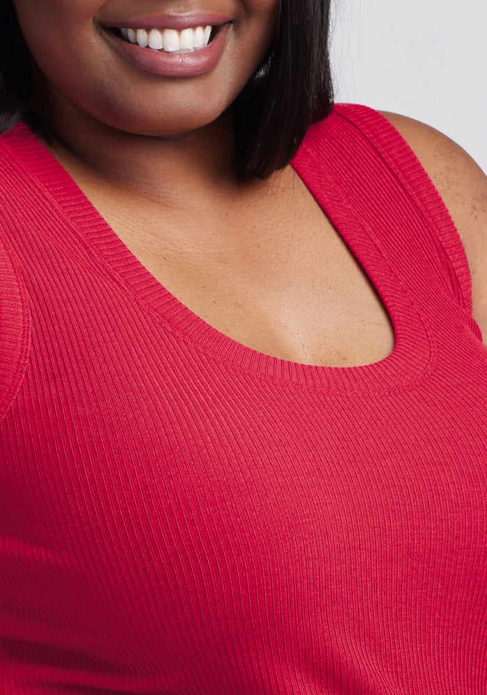 A close-up of a woman smiling, wearing the Woolx Sloane Ribbed Tank in Poppy Spark. Only the lower half of her face, neck, and upper torso are visible.