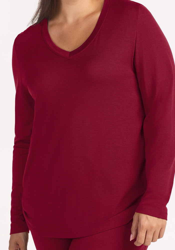 A person wears a deep red, V-neck Lily V Neck Lounge Top - Beet Red merino wool sleep shirt.