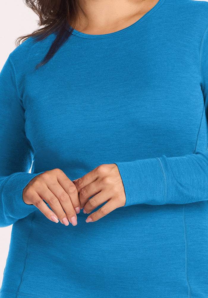 Woman in Woolx Hannah Long Sleeve Top - Blue Razz, hands clasped, showing light pink manicured nails.