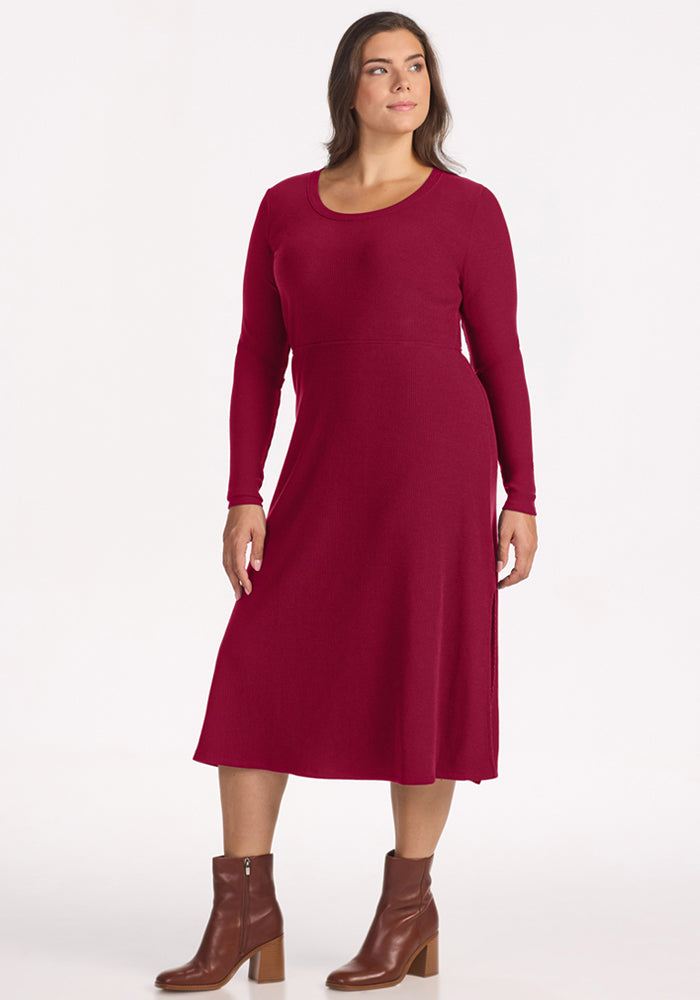 Model wears Woolx Caroline Ribbed Twirl Dress - Beet Red with brown ankle boots, standing against a white background.
